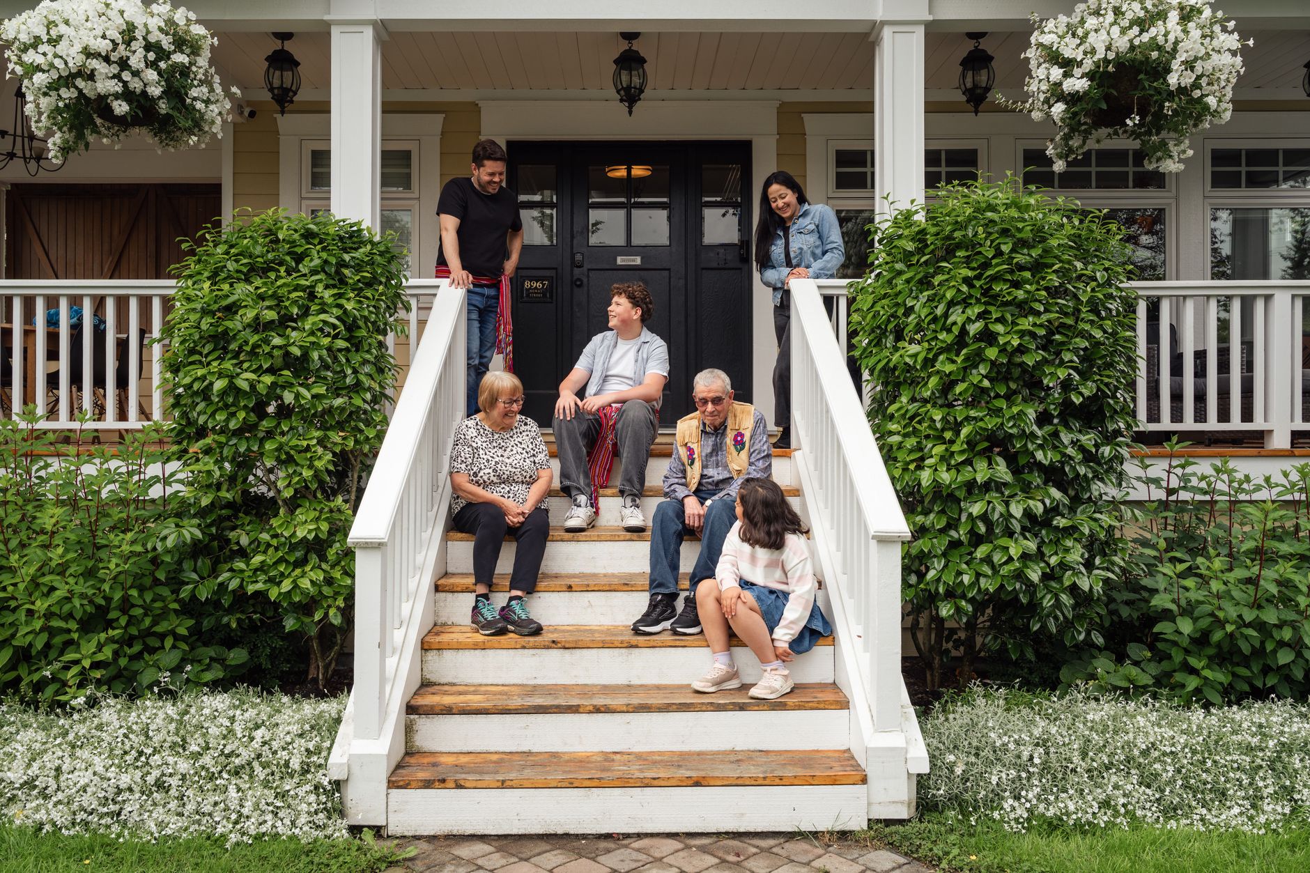 Multigenerational family gathered on the front porch steps of their home